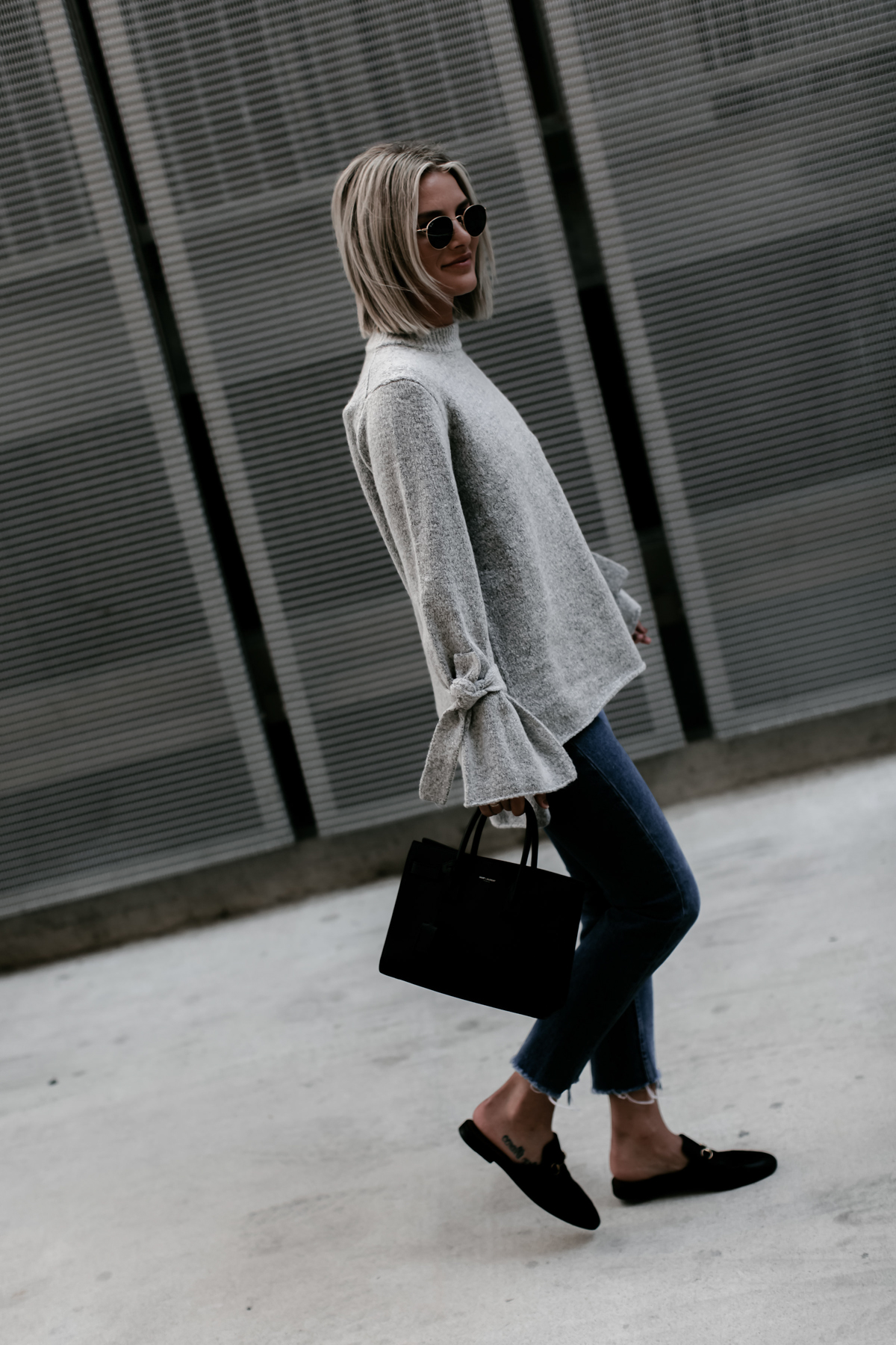 Sage Coralli in a grey tie sleeve sweater and jeans outfit
